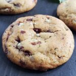 Close up of a mint chocolate chip cookie on a dark surface.
