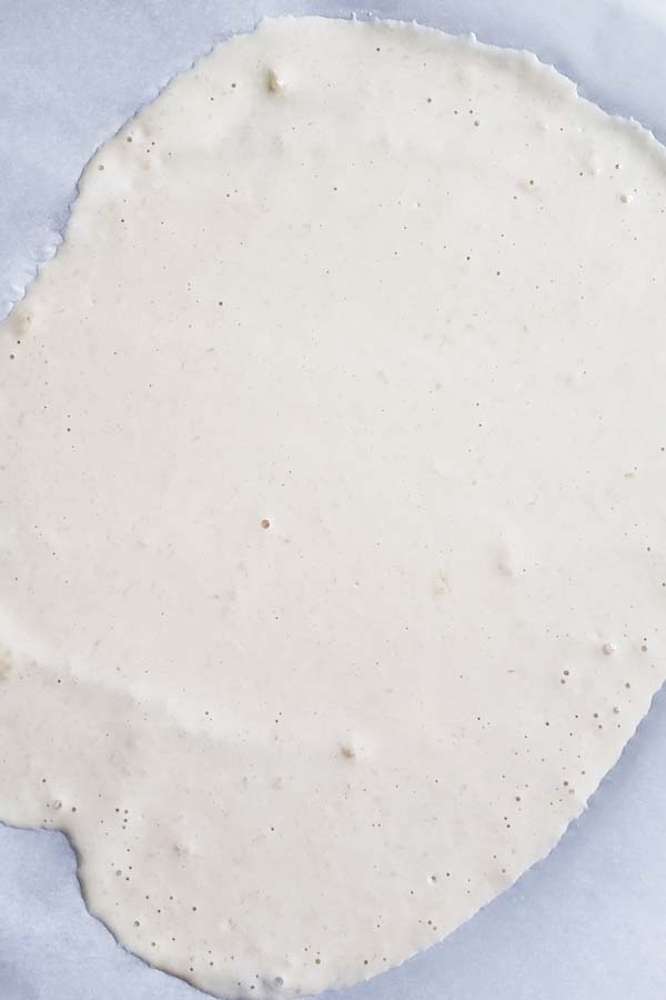 Sourdough cracker batter spread thinly on parchment paper.