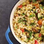 tomatoes and macaroni with summer vegetables in a blue dutch oven
