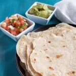 Close up of a stack of sourdough tortillas on a blue background.