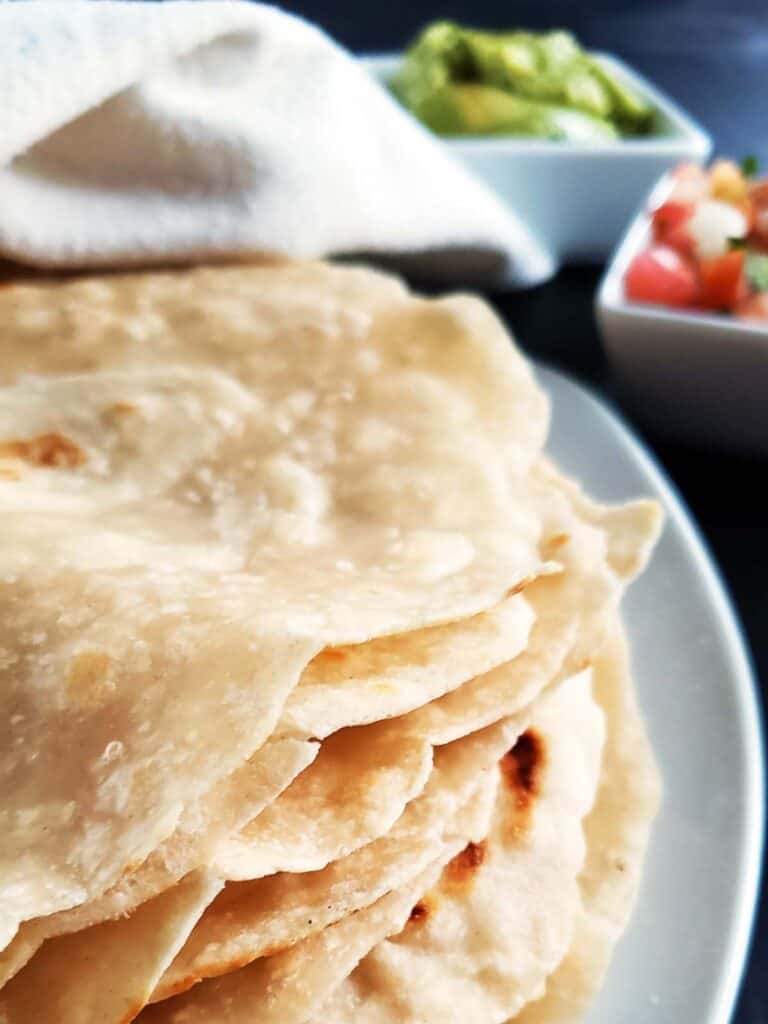Stack of sourdough tortillas on a white plate.