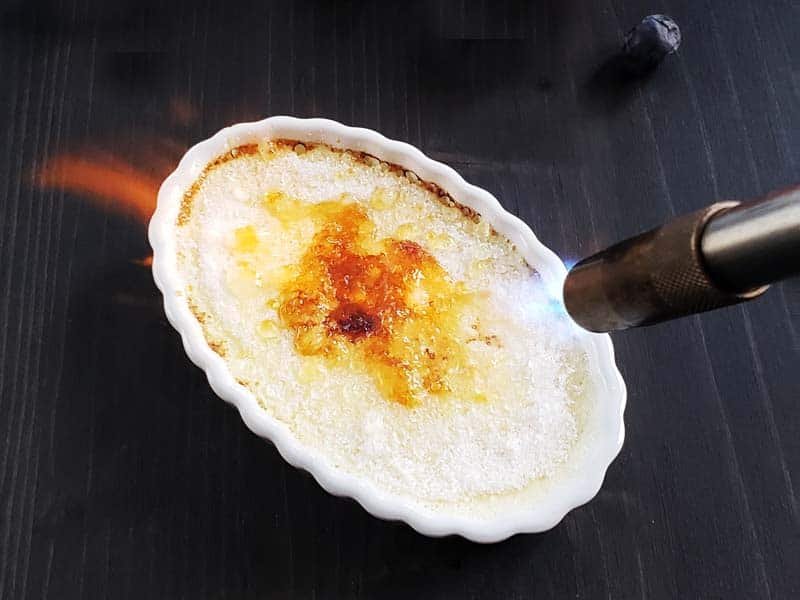 Bruleeing sugar on creme brulee with a torch.