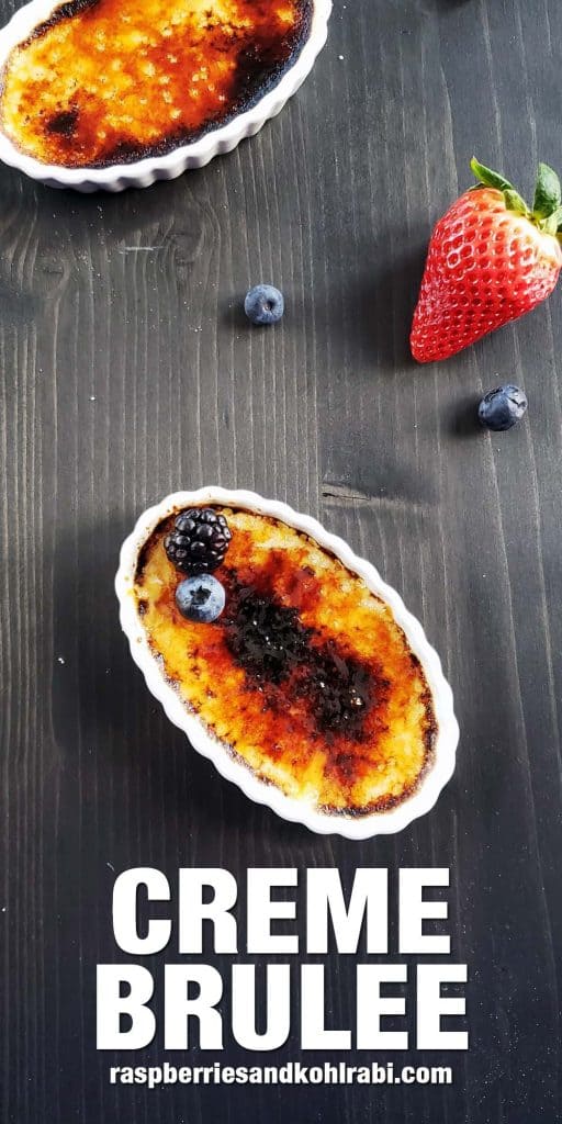 Creme brulee on a dark surface surrounded by berries.