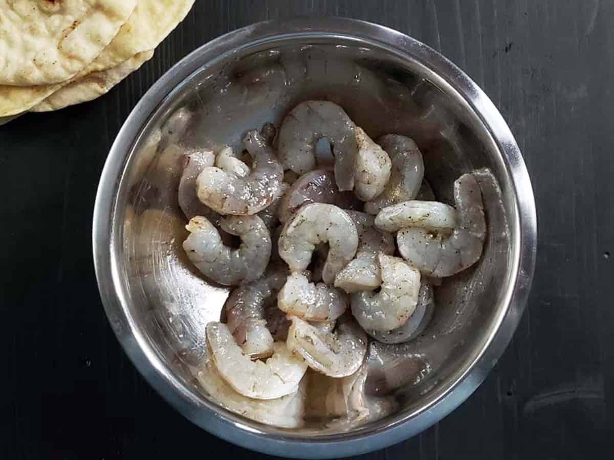 Raw shrimp in a metal bowl.