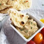 Piece of flatbread in hummus.