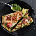 two slices of shrimp pesto flatbread on a black plate