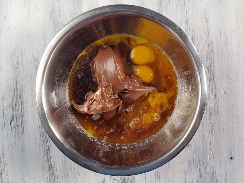Nutella, eggs, and browned butter in a metal bowl.