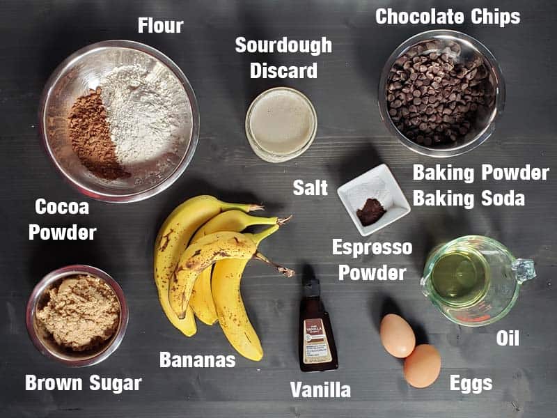 Sourdough chocolate banana bread ingredients on a dark surface.