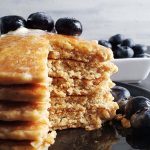 close up of a stack of sourdough oatmeal pancakes topped with blueberries