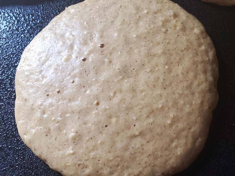 Sourdough oatmeal pancake cooking on a griddle.