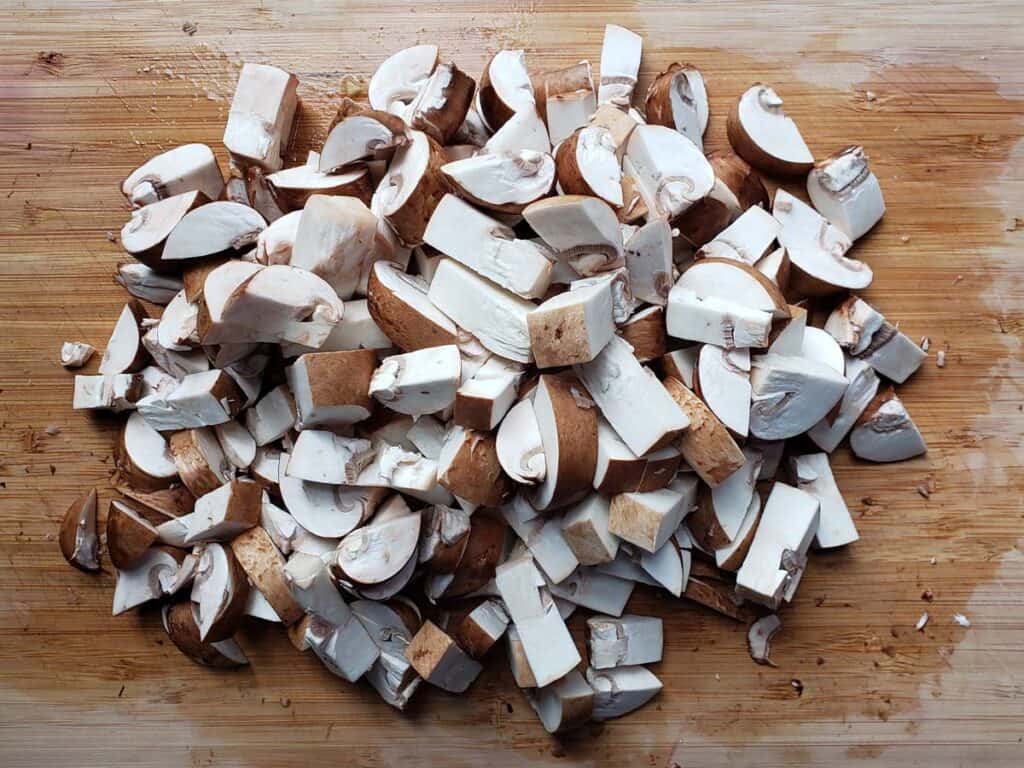 Chopped mushrooms on a wooden cutting board.