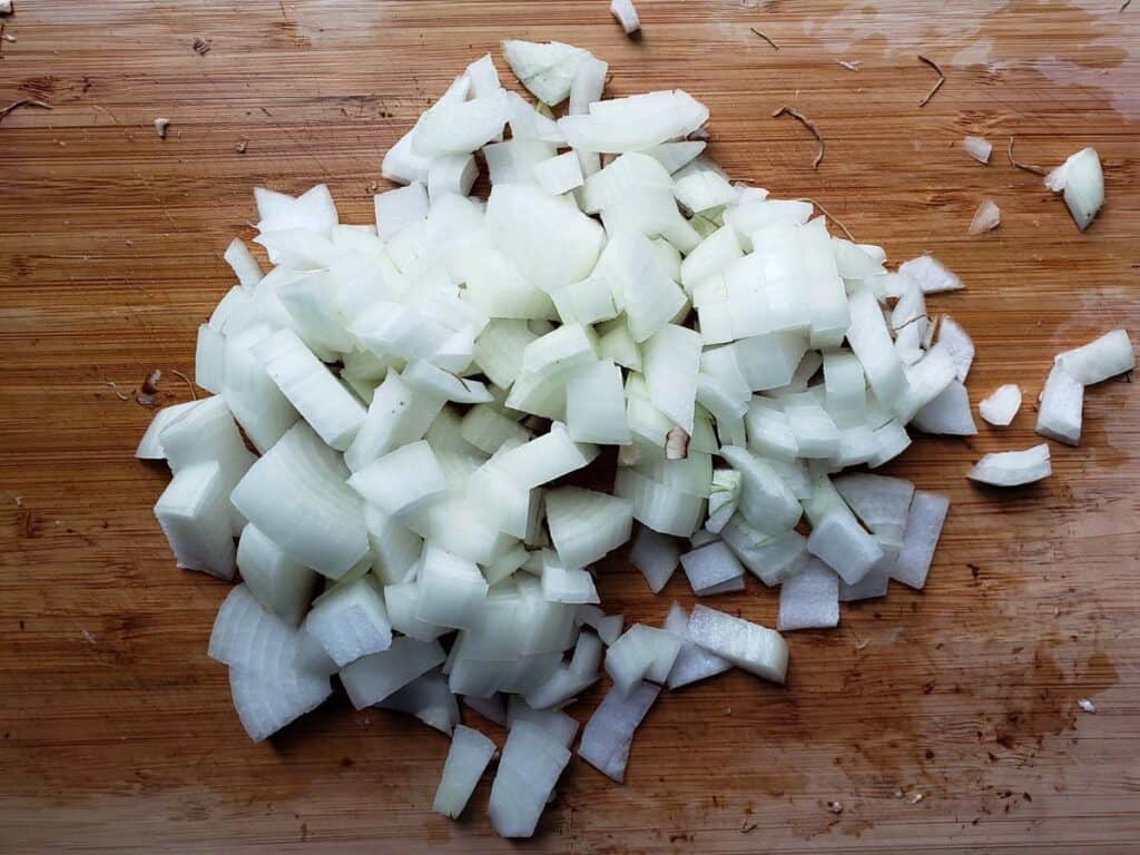 Chopped onion on a wooden cutting board.