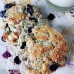 close up of two sourdough blueberry thyme scones on white paper