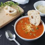 white bowl filled with tomato soup on a dark background