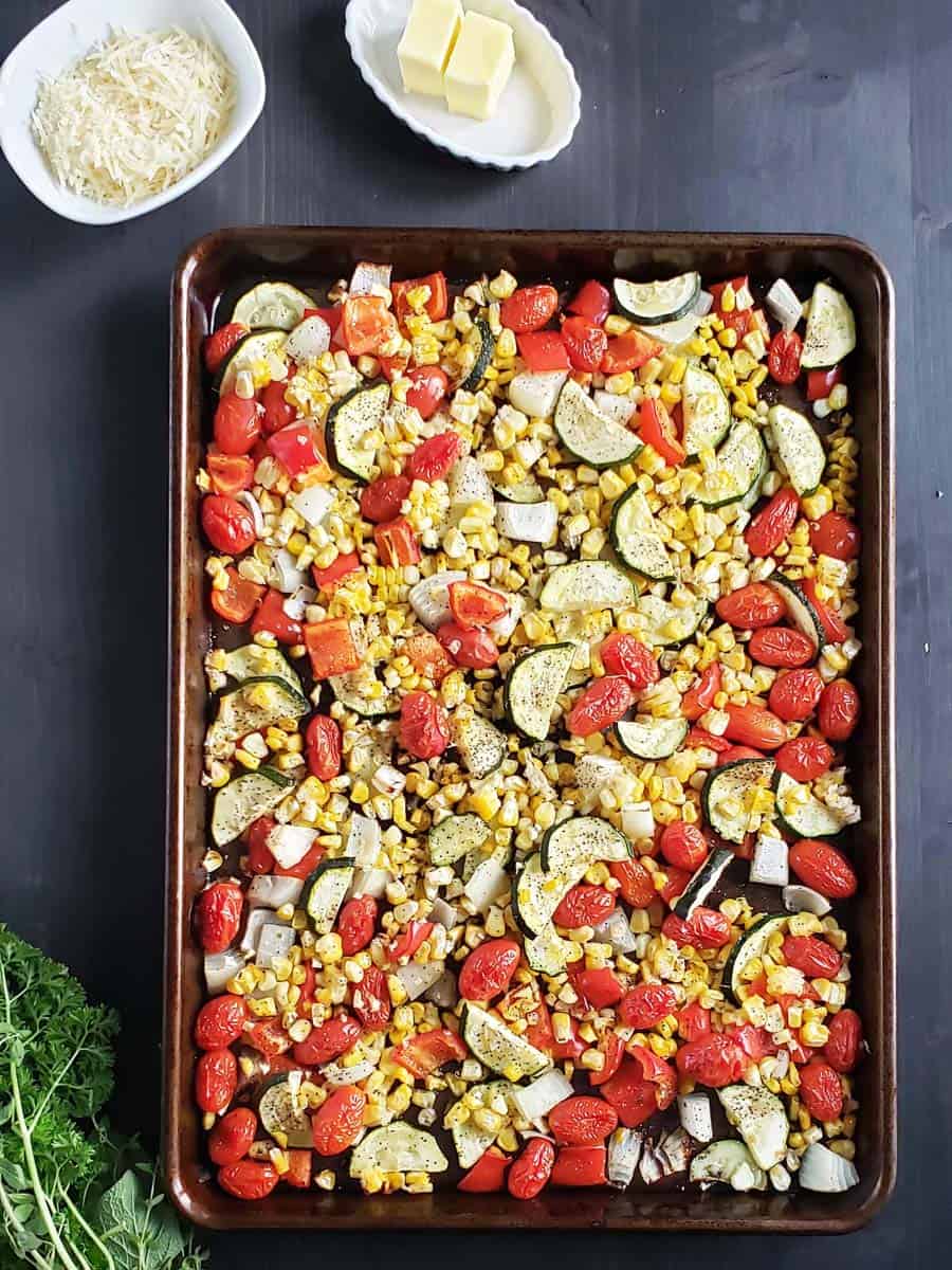Roasted mixed summer vegetables on a sheet pan.