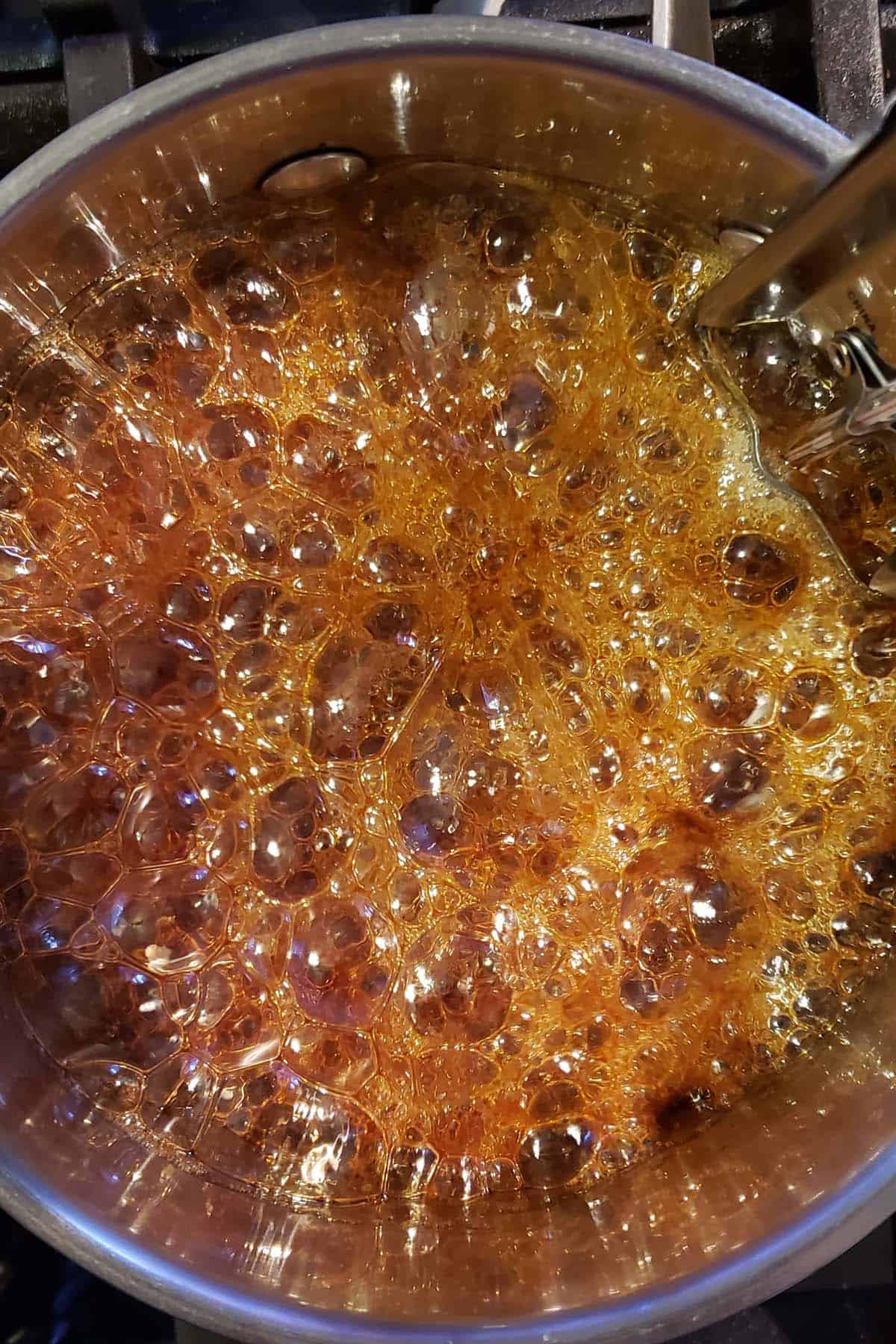 Boiling sugar and honey in a saucepan dark amber color.