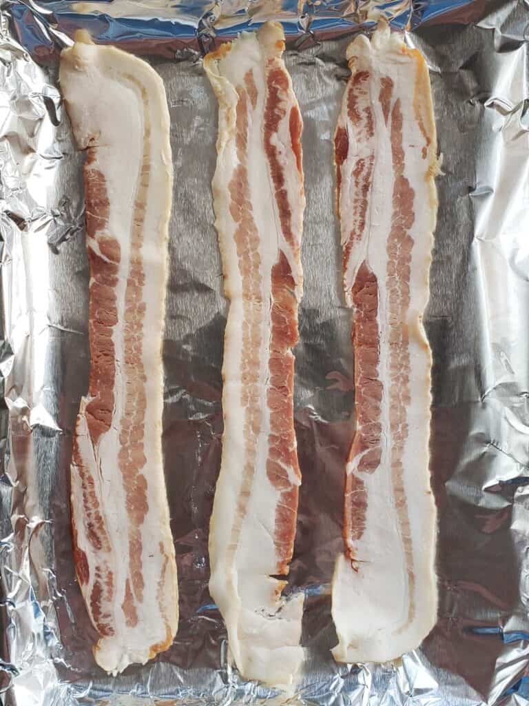 Uncooked bacon on foil.