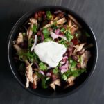 black bowl filled with pork, black bean, and pumpkin stew