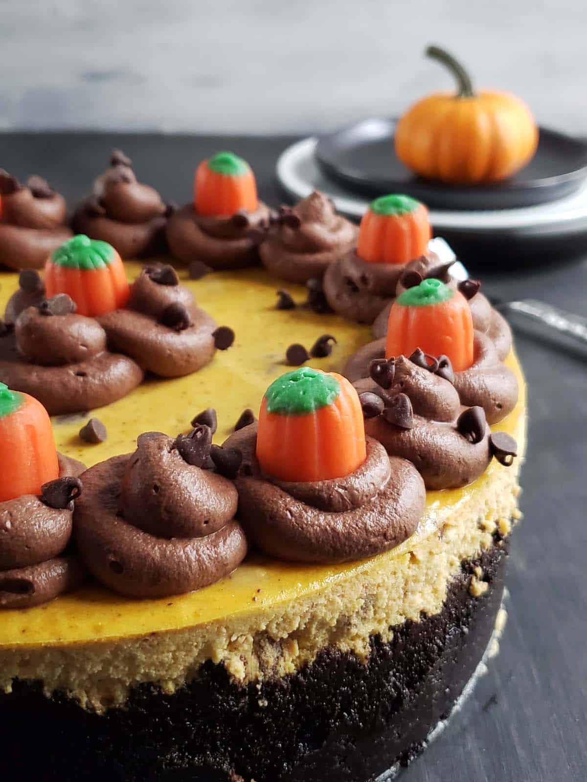 Whole pumpkin cheesecake topped with chocolate whipped cream and candy pumpkins.