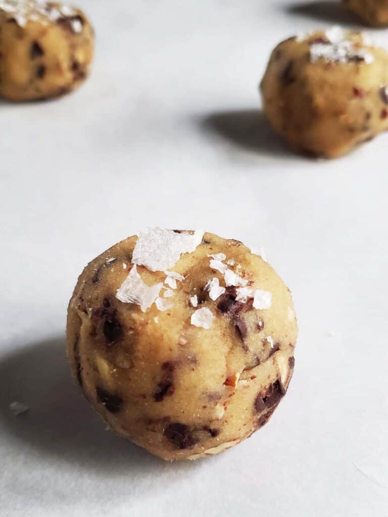 Ball of cookie dough topped with flakey salt.