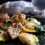 meatballs, ravioli, and spinach piled on a black plate