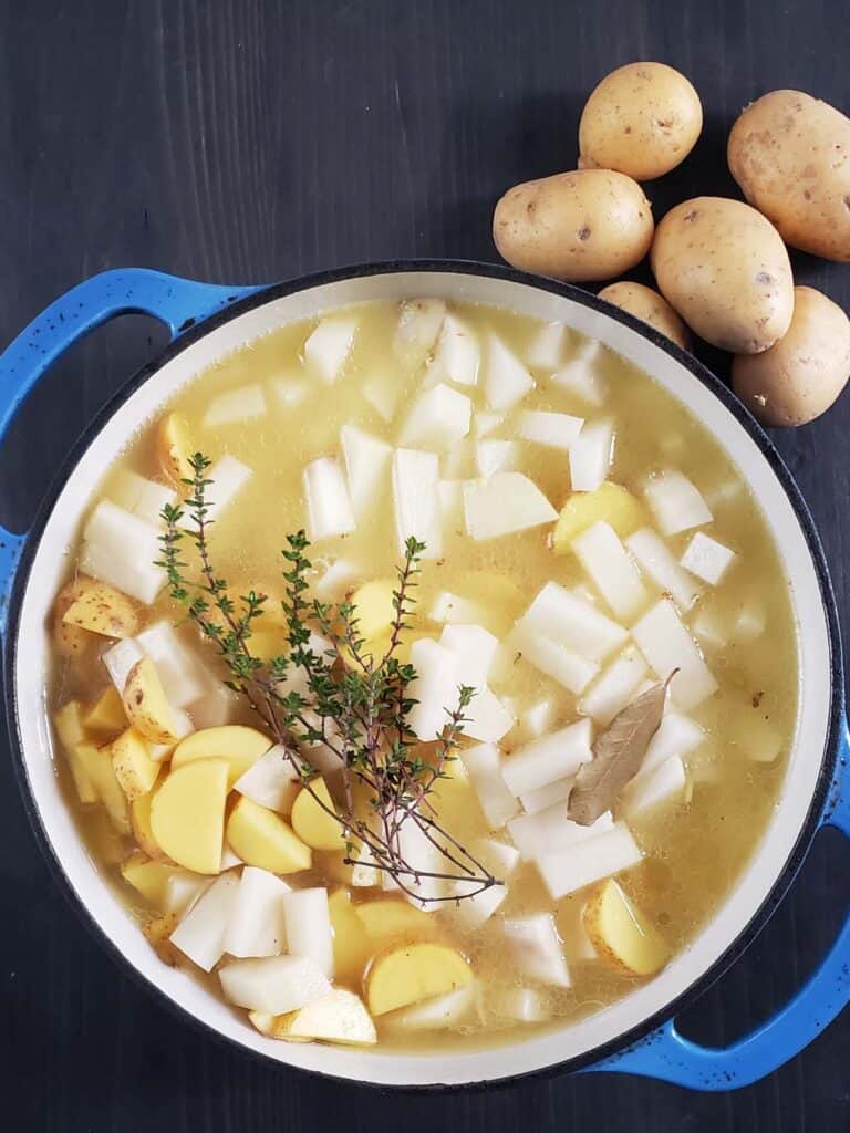 Potatoes and chicken broth in a dutch oven.