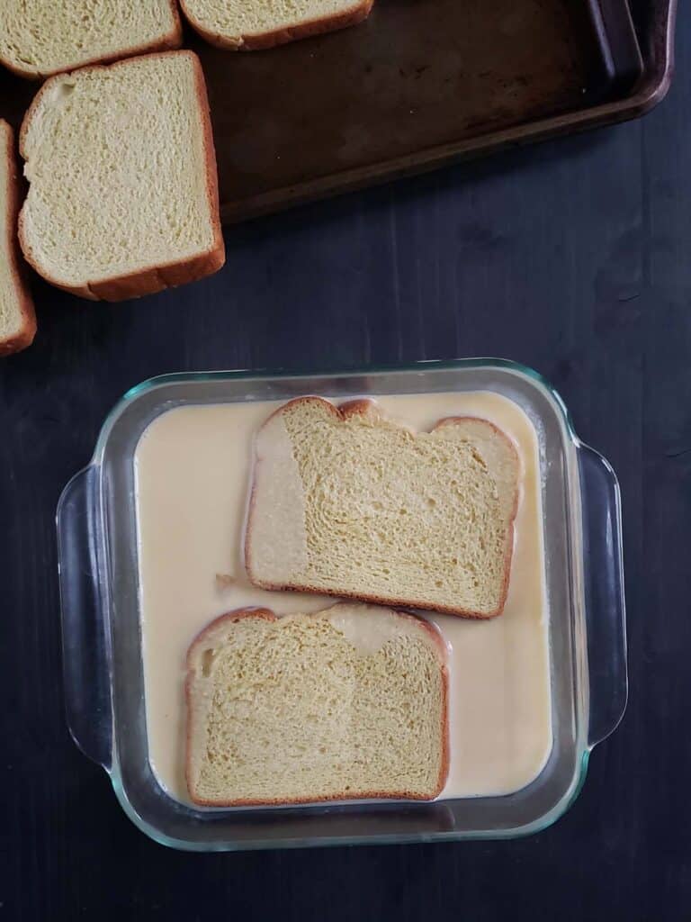 two slices of bread soaking in custard
