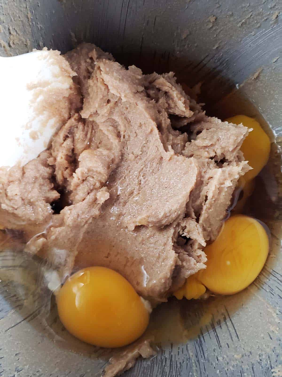 Butter and sugar creamed together with three yolks on top in a metal bowl.