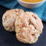 Two ham and cheese sourdough scones on a dark background.