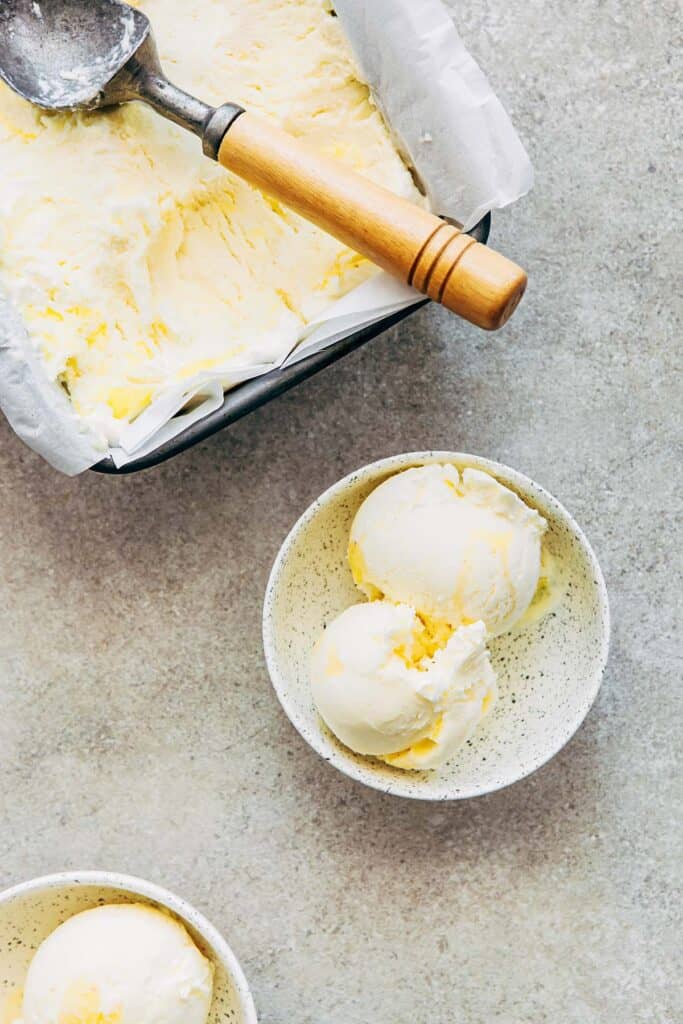 scoops of lemon curd ice cream in white speckled bowls