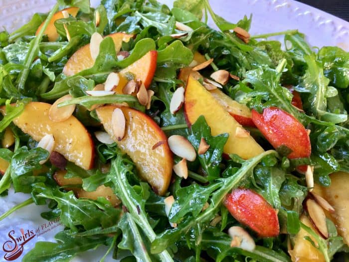peach arugula salad on a white plate