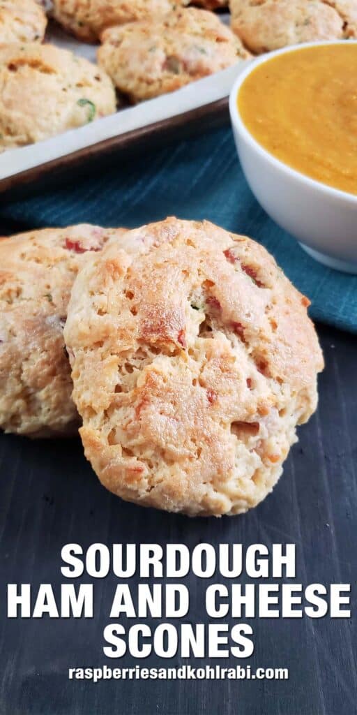 Two sourdough ham and cheese scones in front of a bowl of soup.