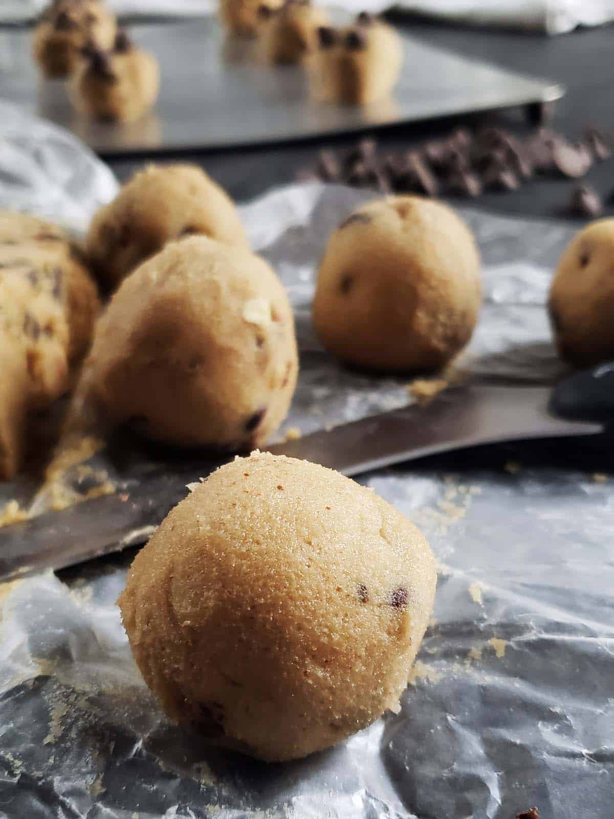 Chocolate chip cookie dough balls on wax paper.