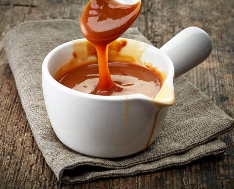 caramel sauce pouring into a white bowl