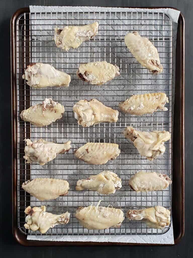 Raw chicken wings on a wire cooling rack.