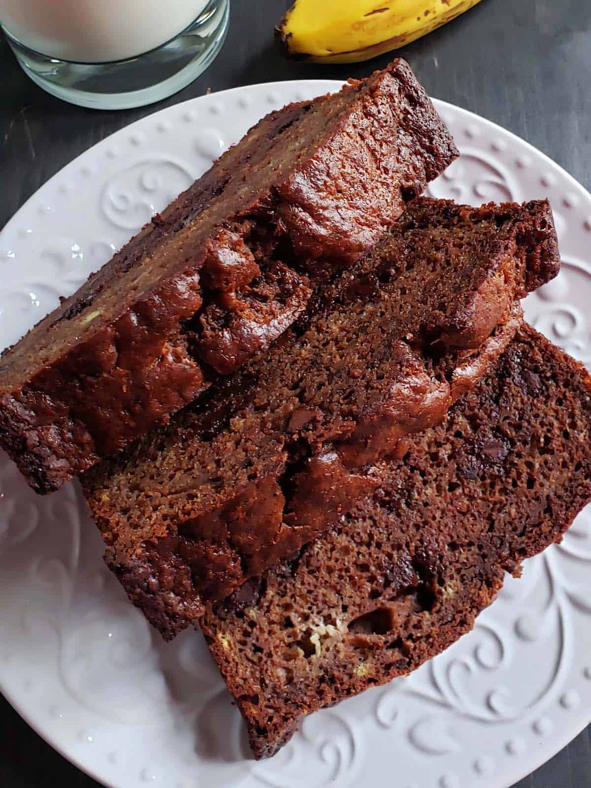 Three slices of chocolate banana bread on a white plate.
