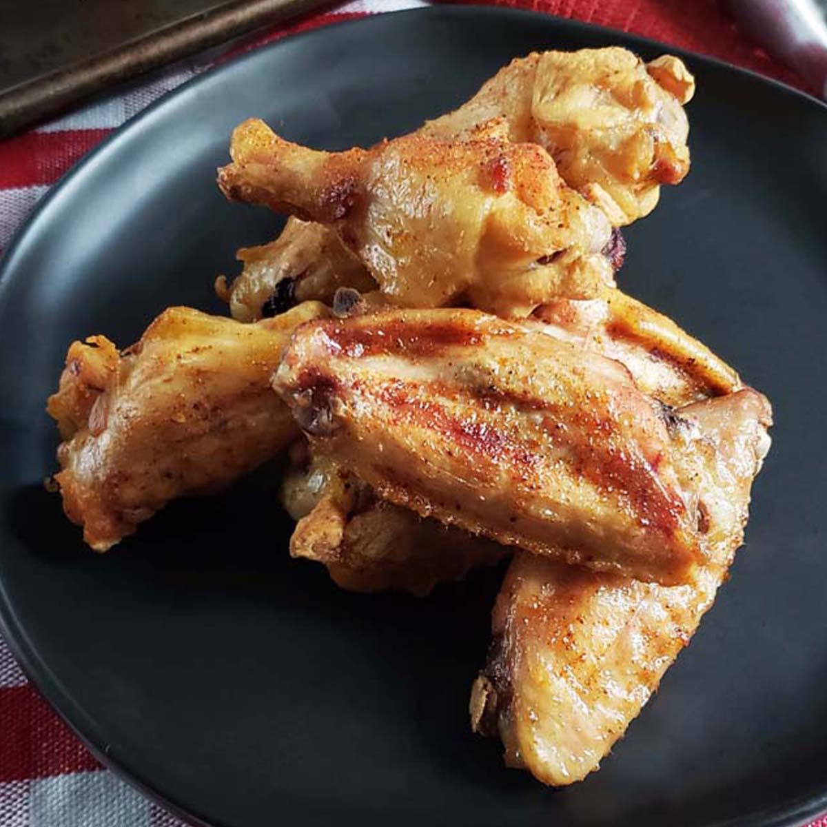 Stack of chicken wings on a black plate.