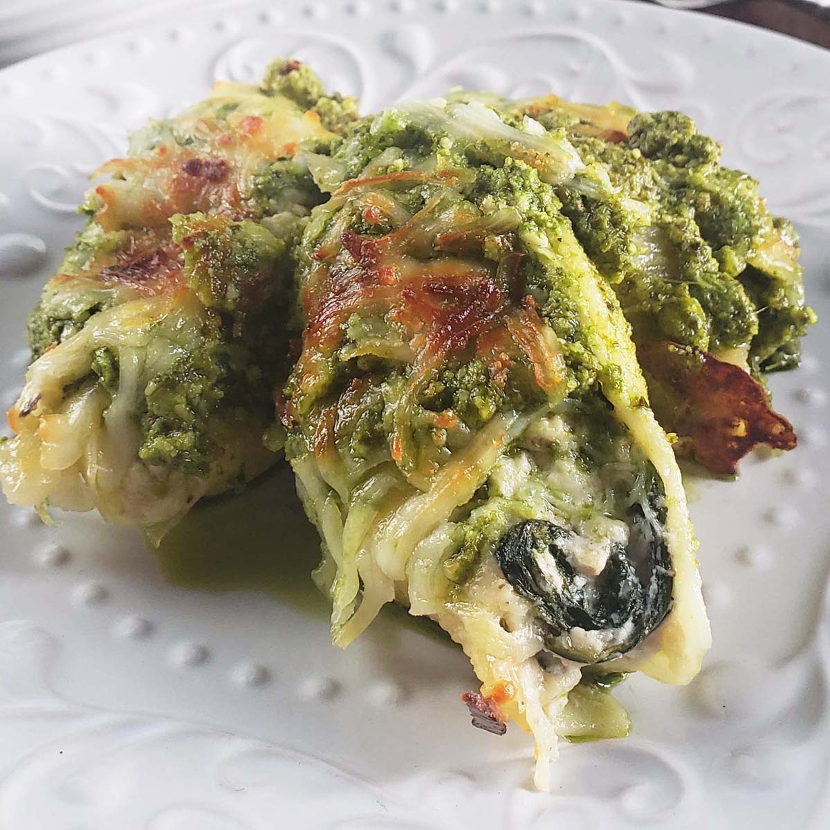 Three pesto stuffed shells on a white plate.