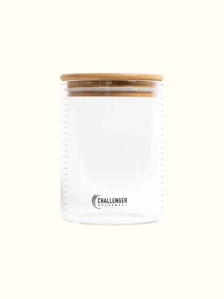 Large glass sourdough storage container with a wooden lid.