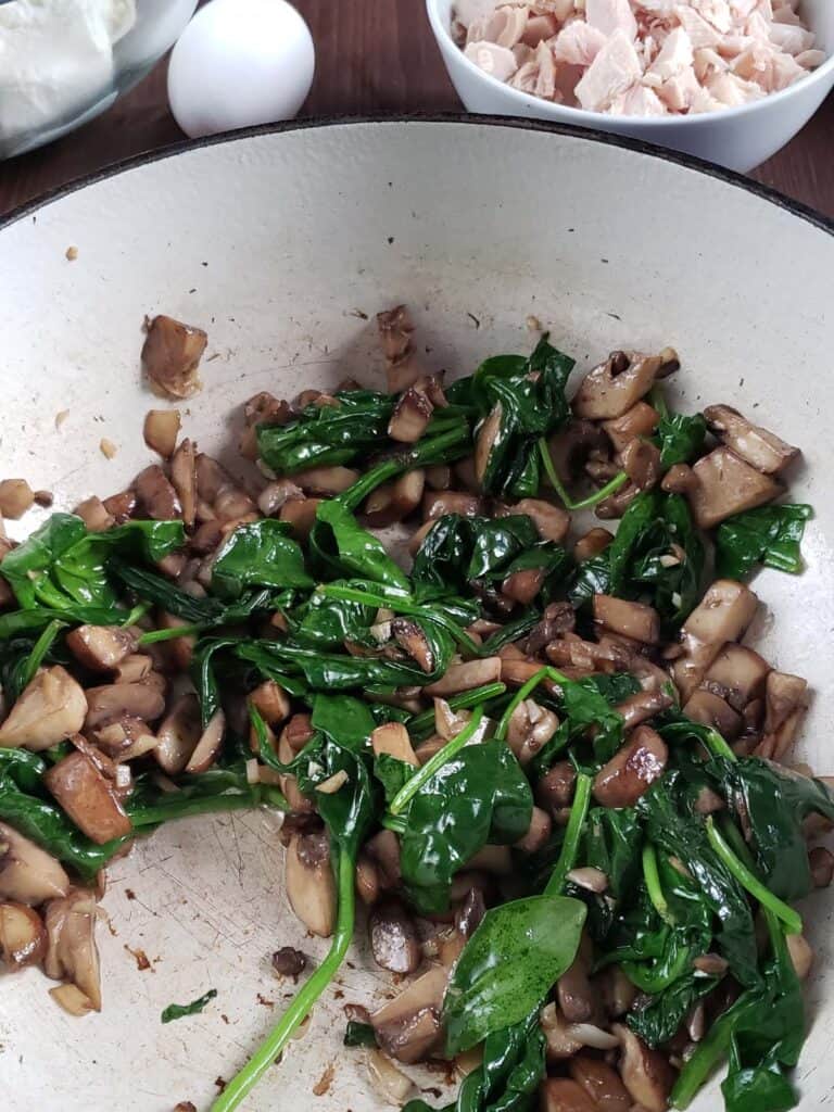 Sauteed spinach and mushrooms in a dutch oven.