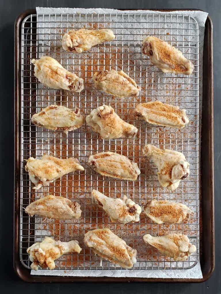 Raw seasoned chicken wings on a wire cooling rack.
