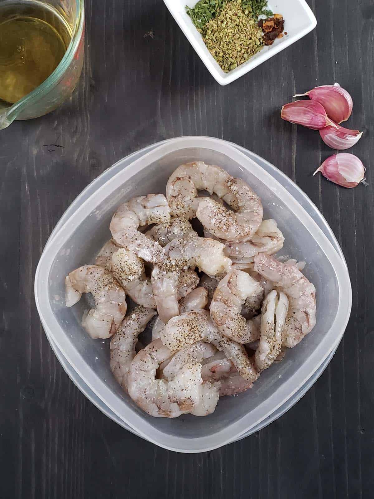 Raw shrimp in a square plastic container.