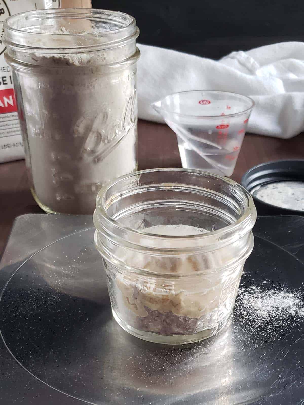 Close up of a small glass jar filled with sourdough starter.