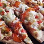 Close-up of crab rangoon pizza topped with sweet chili sauce.