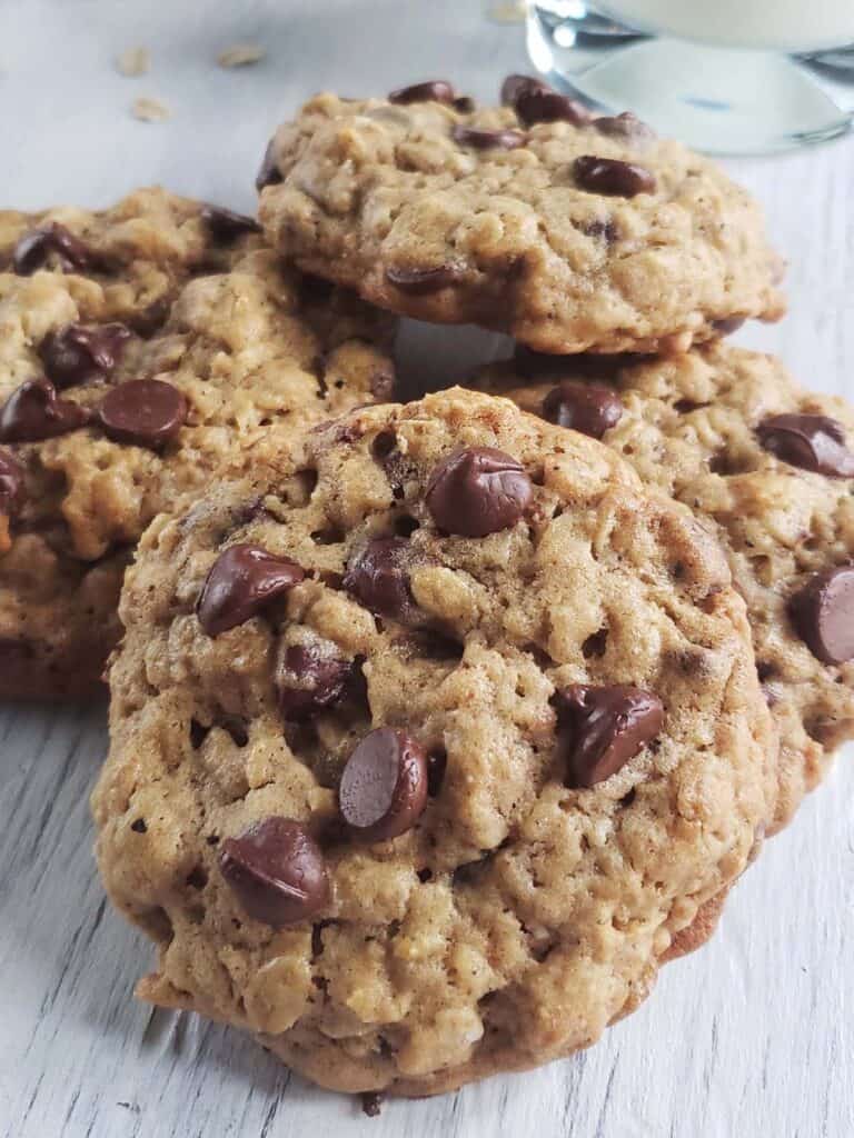 Pile of sourdough oatmeal chocolate chip cookies on a white surface.