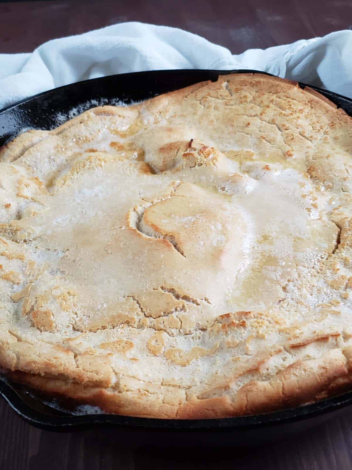 Baked sourdough dutch baby in a cast iron skillet.