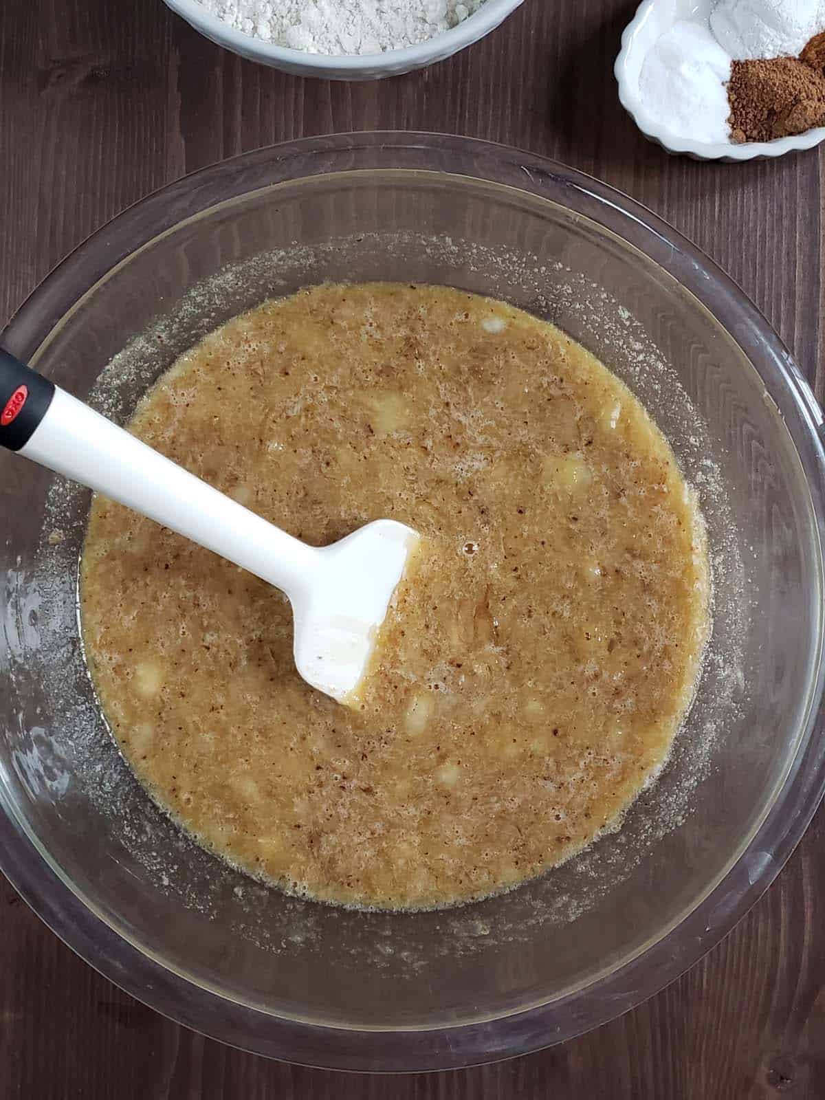 Banana bread wet ingredients mixed together in a glass bowl.