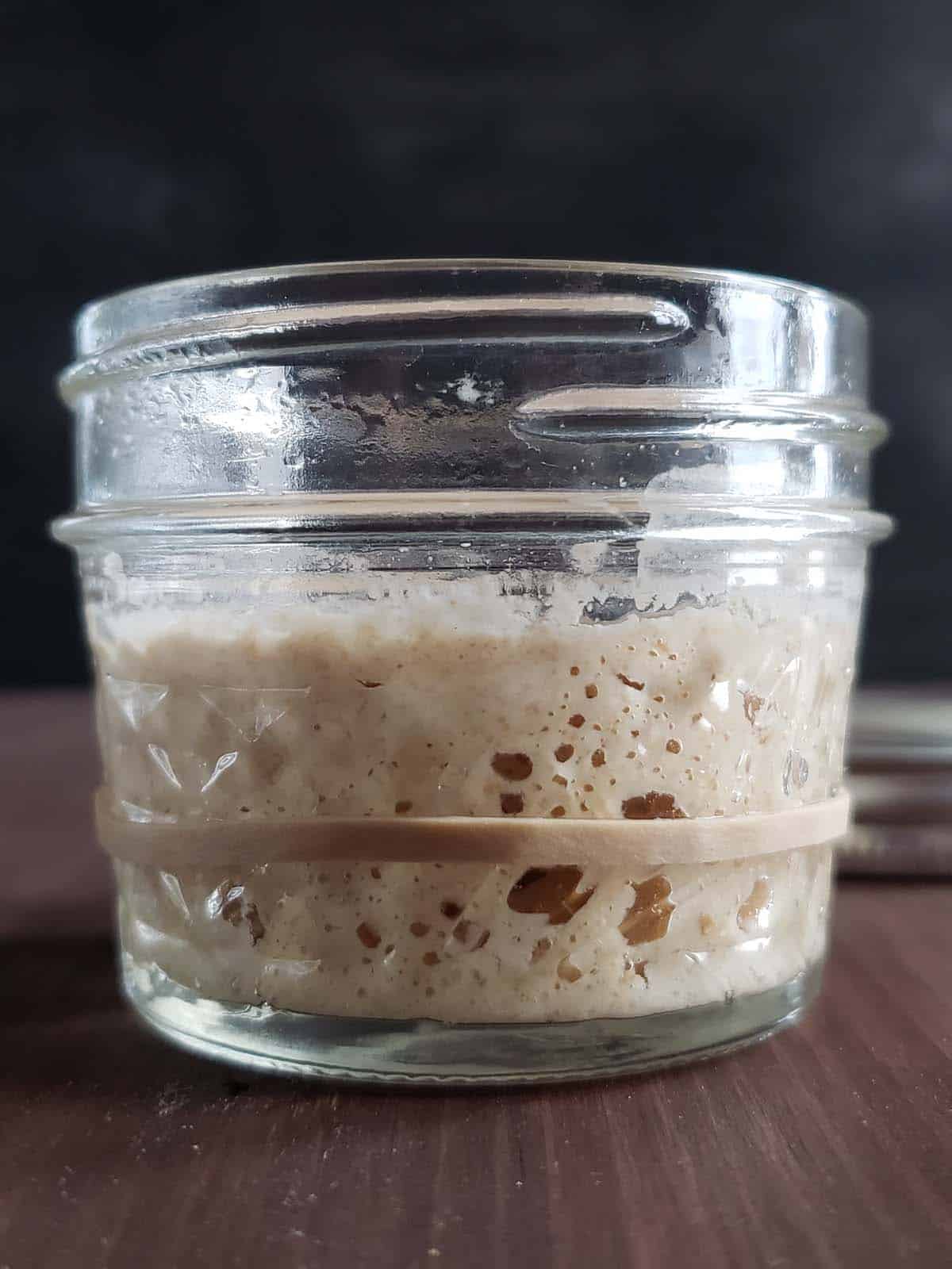 Sourdough starter that has doubled in size in a glass jar.