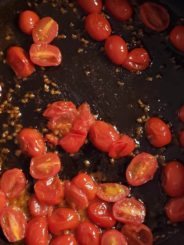Sauteed cherry tomatoes in a skillet.