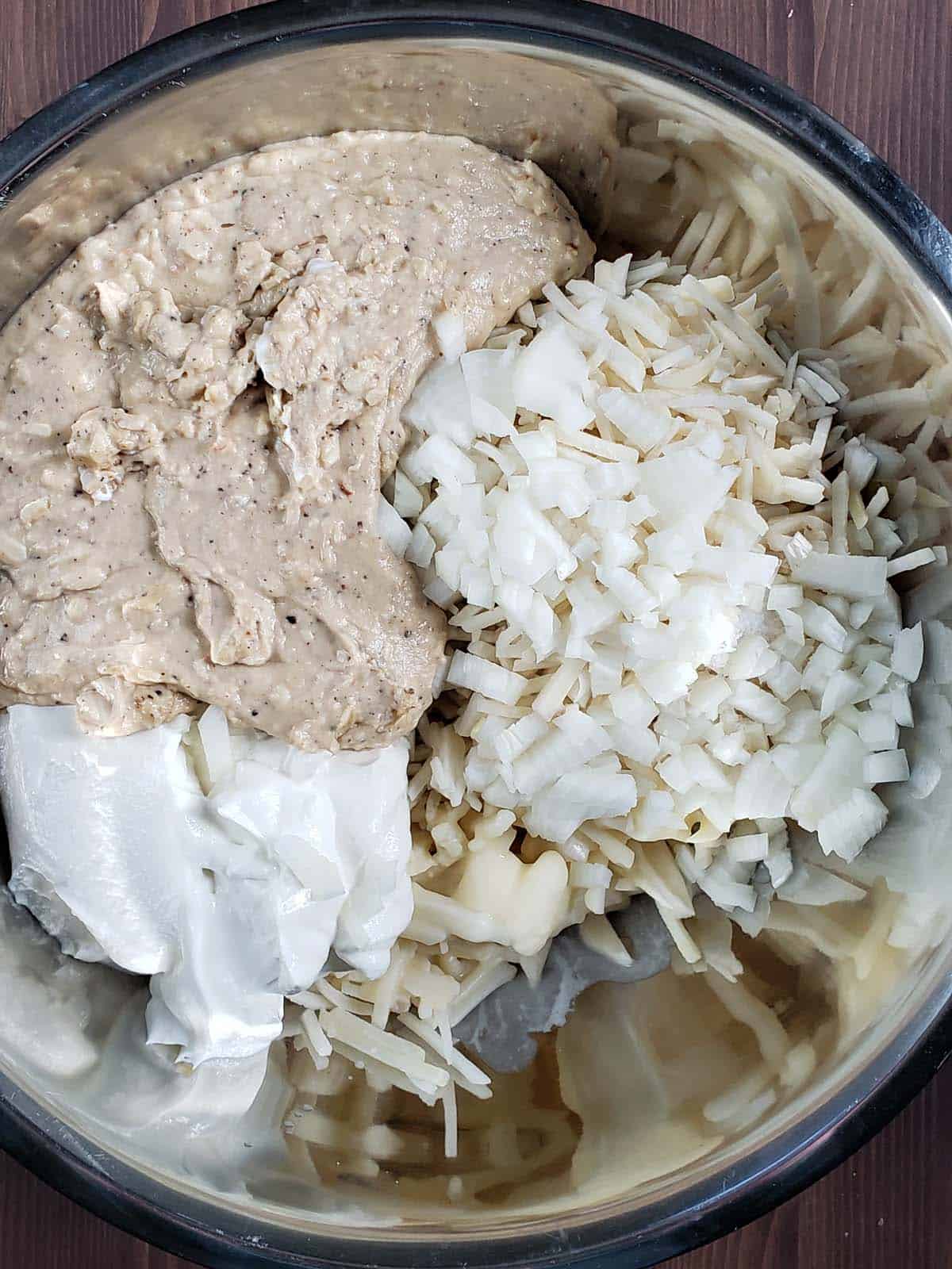 Hash brown casserole ingredients in a metal bowl.